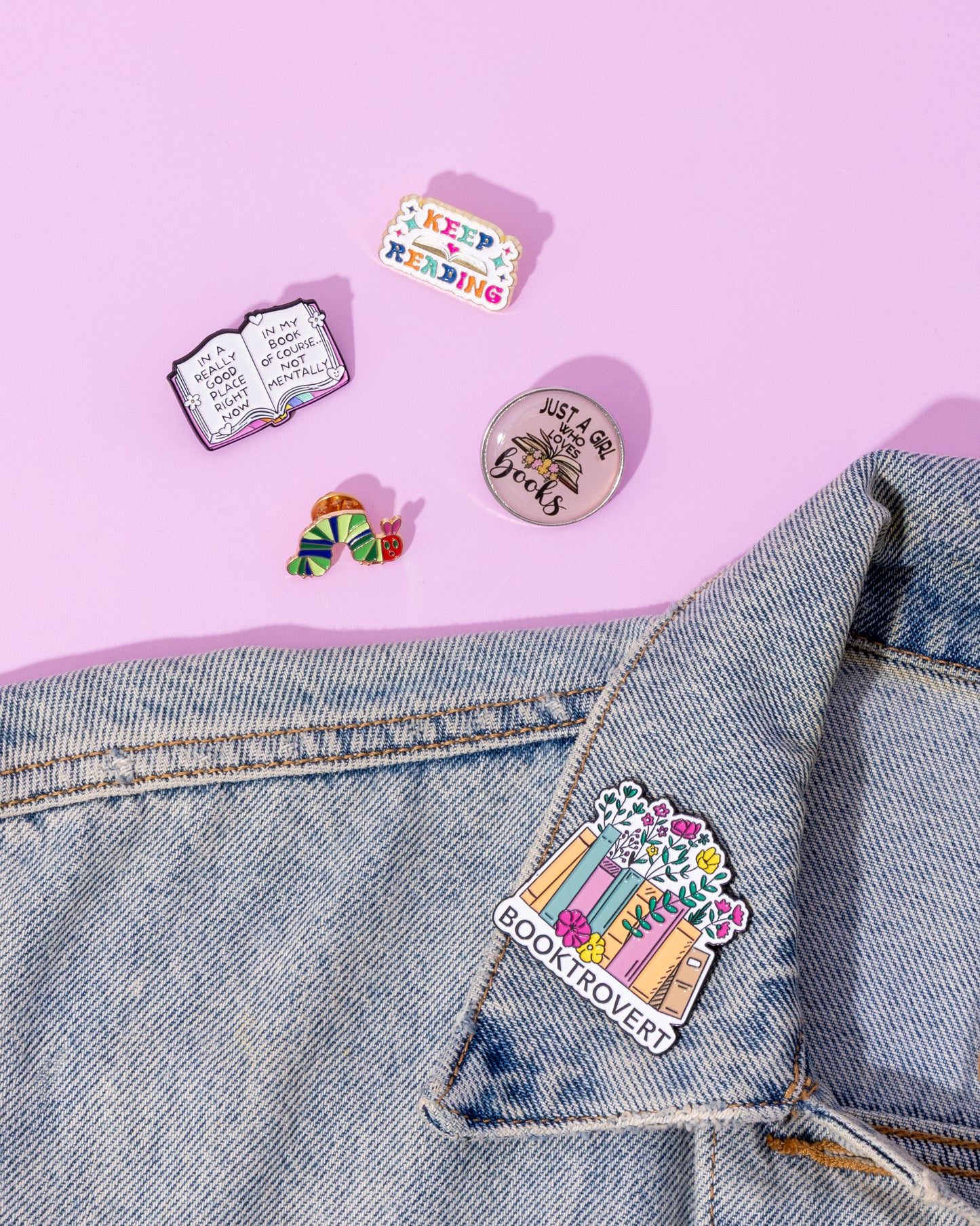 Colorful pins on a denim jacket against a pink background