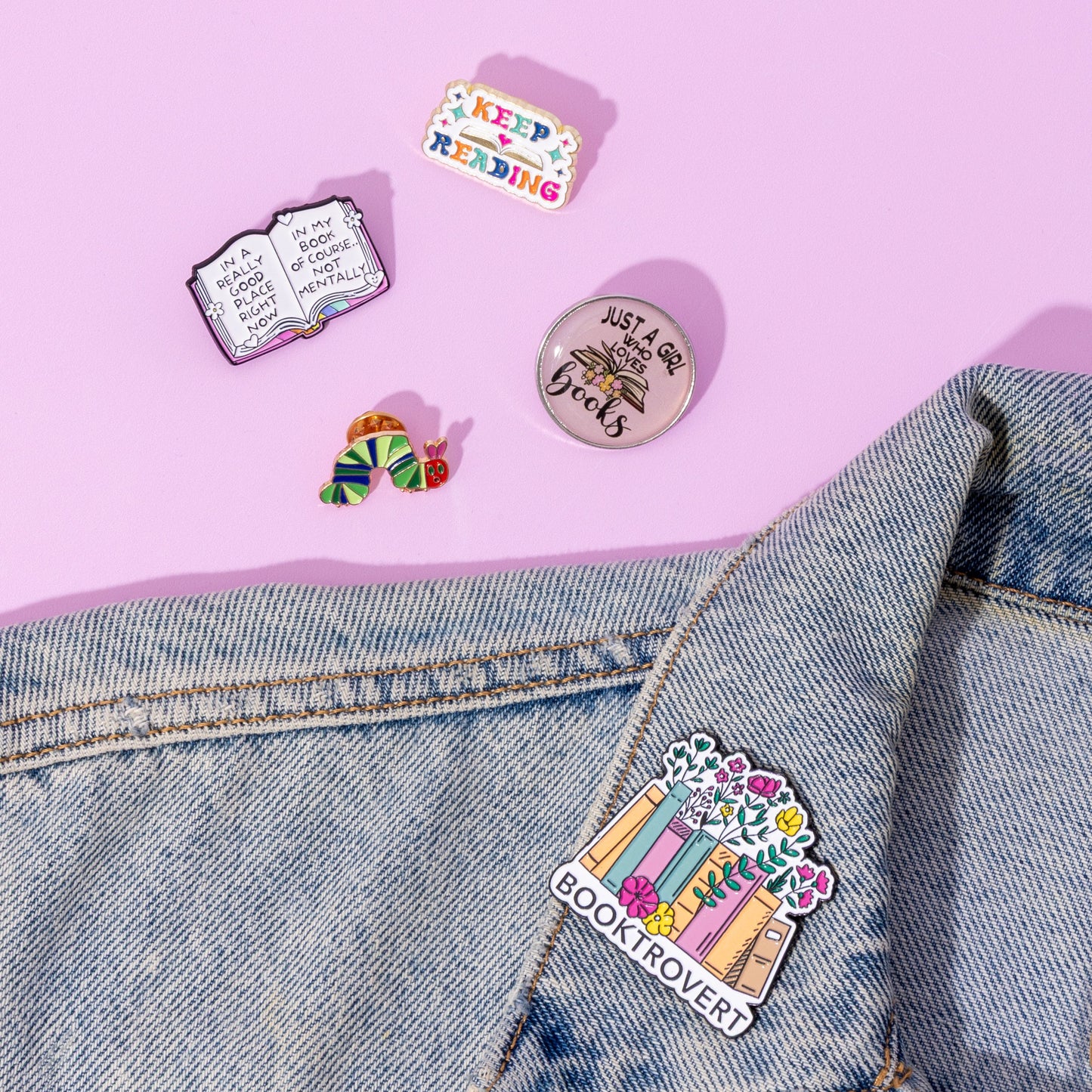 Colorful pins on a denim jacket against a pink background