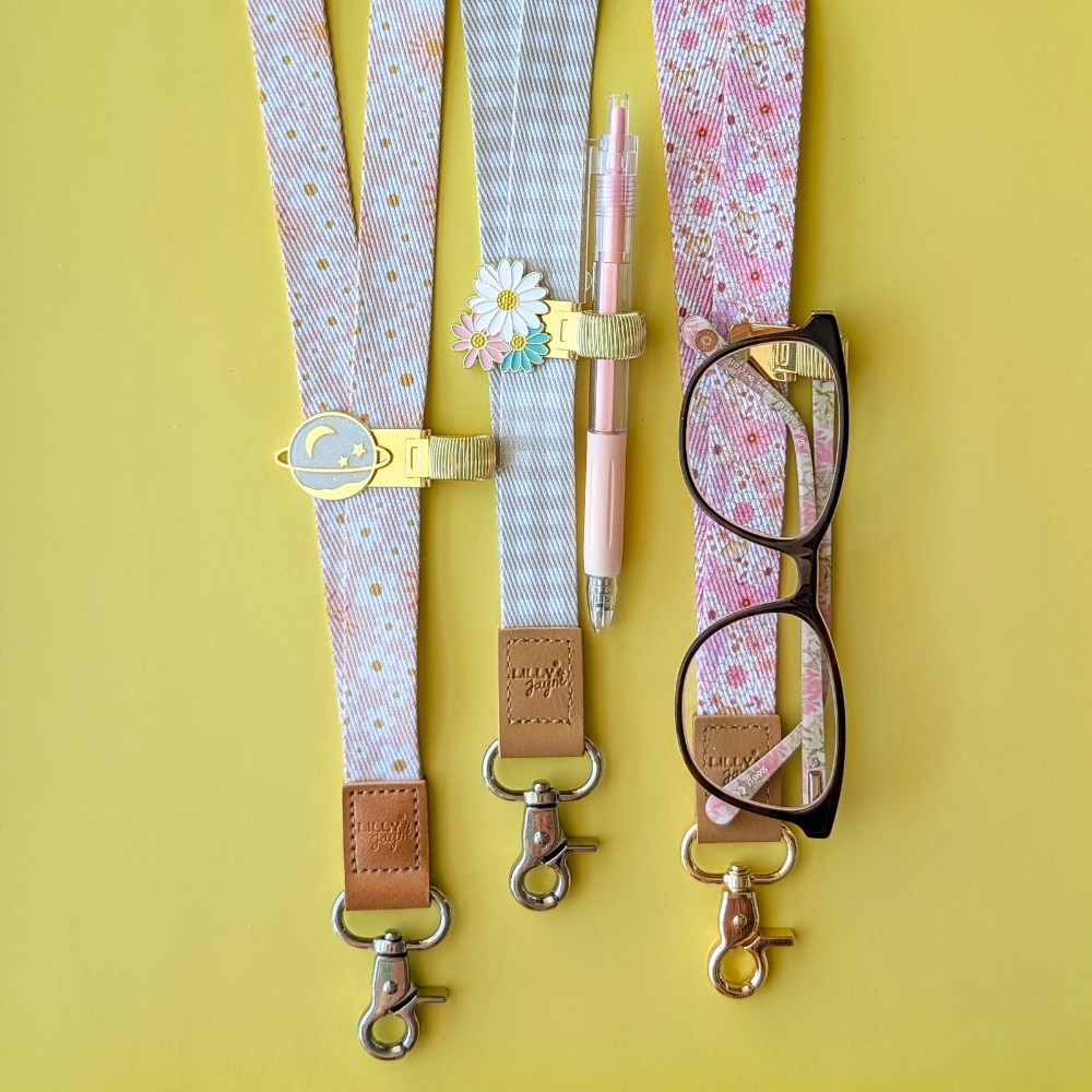 Glasses case with floral strap, pen holder, and glasses on a yellow background