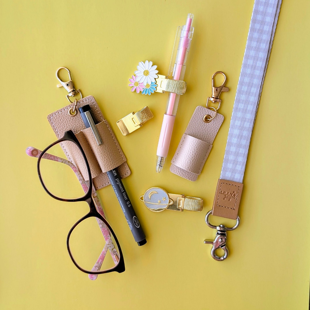 Collection of stationery items including glasses, pen, and keychains on a yellow background