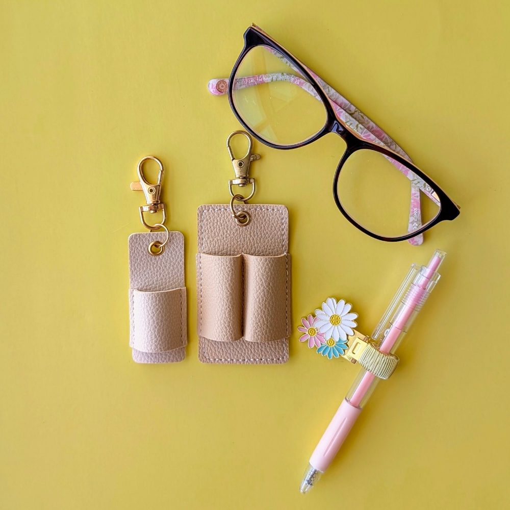 Glasses, keychain pouches, pen, and flower on a yellow background