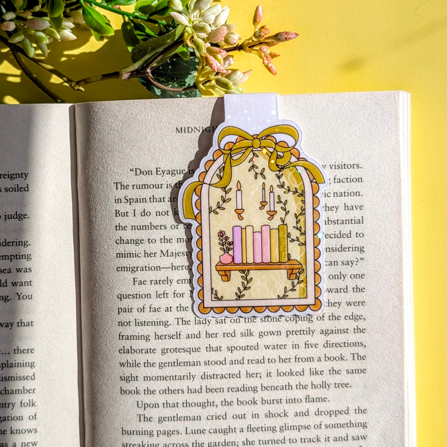 Decorative bookmark with candles on an open book against a yellow background