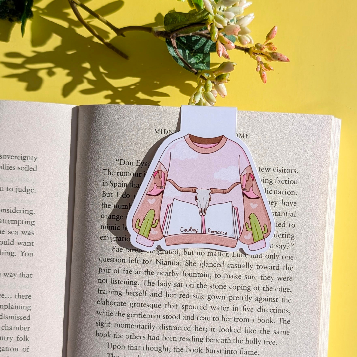 Sticker of a shirt with a graphic design on an open book with a yellow background