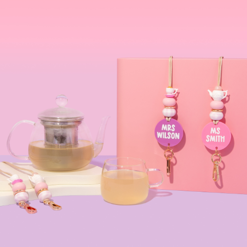 Tea set with personalized keychains on a pink background