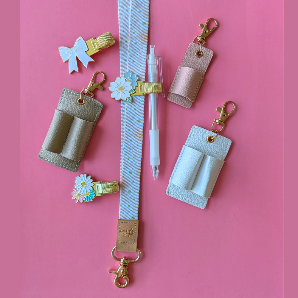 Collection of small accessories including hair clips, a pen, and keychains on a pink background
