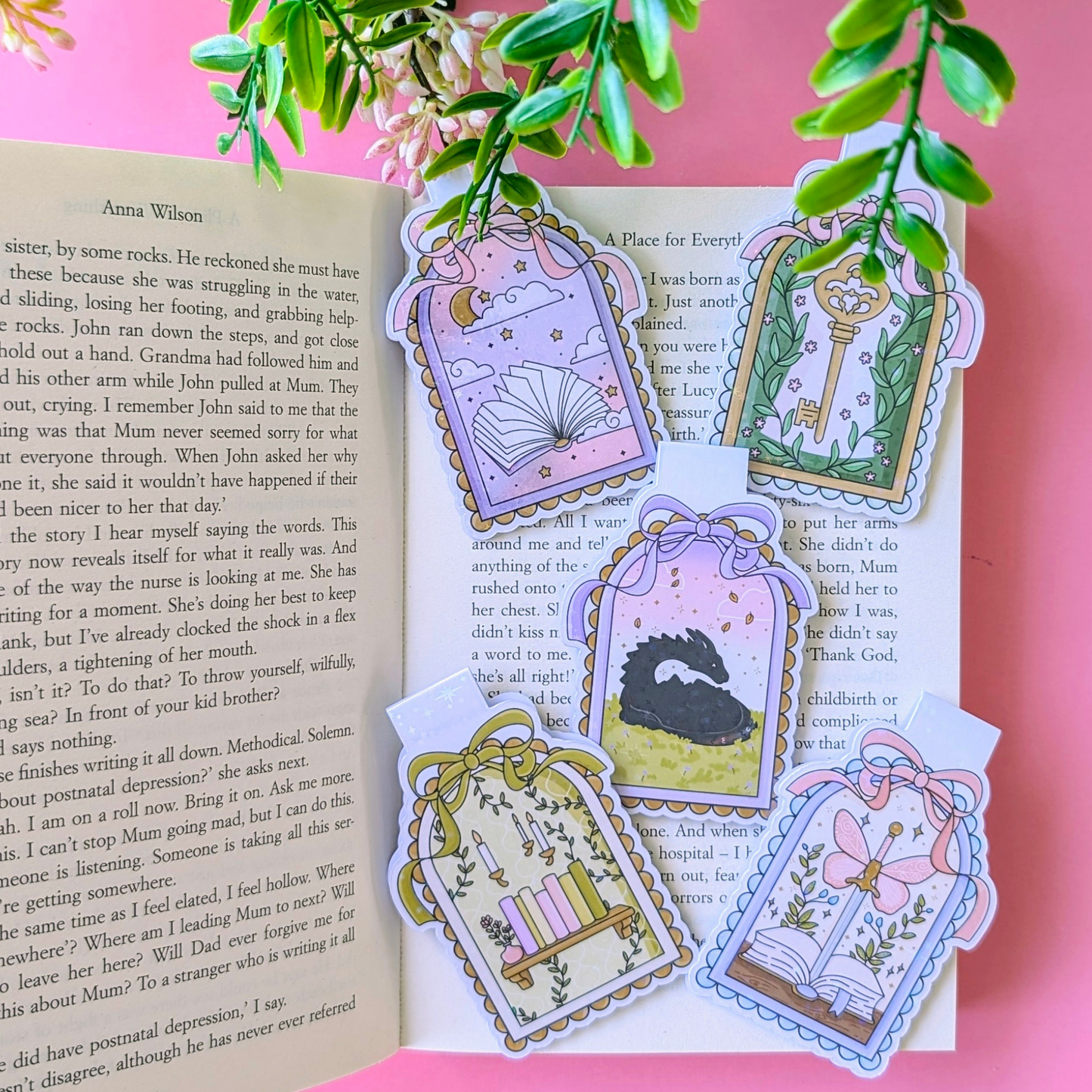 Decorative bookmarks with illustrations on an open book against a pink background