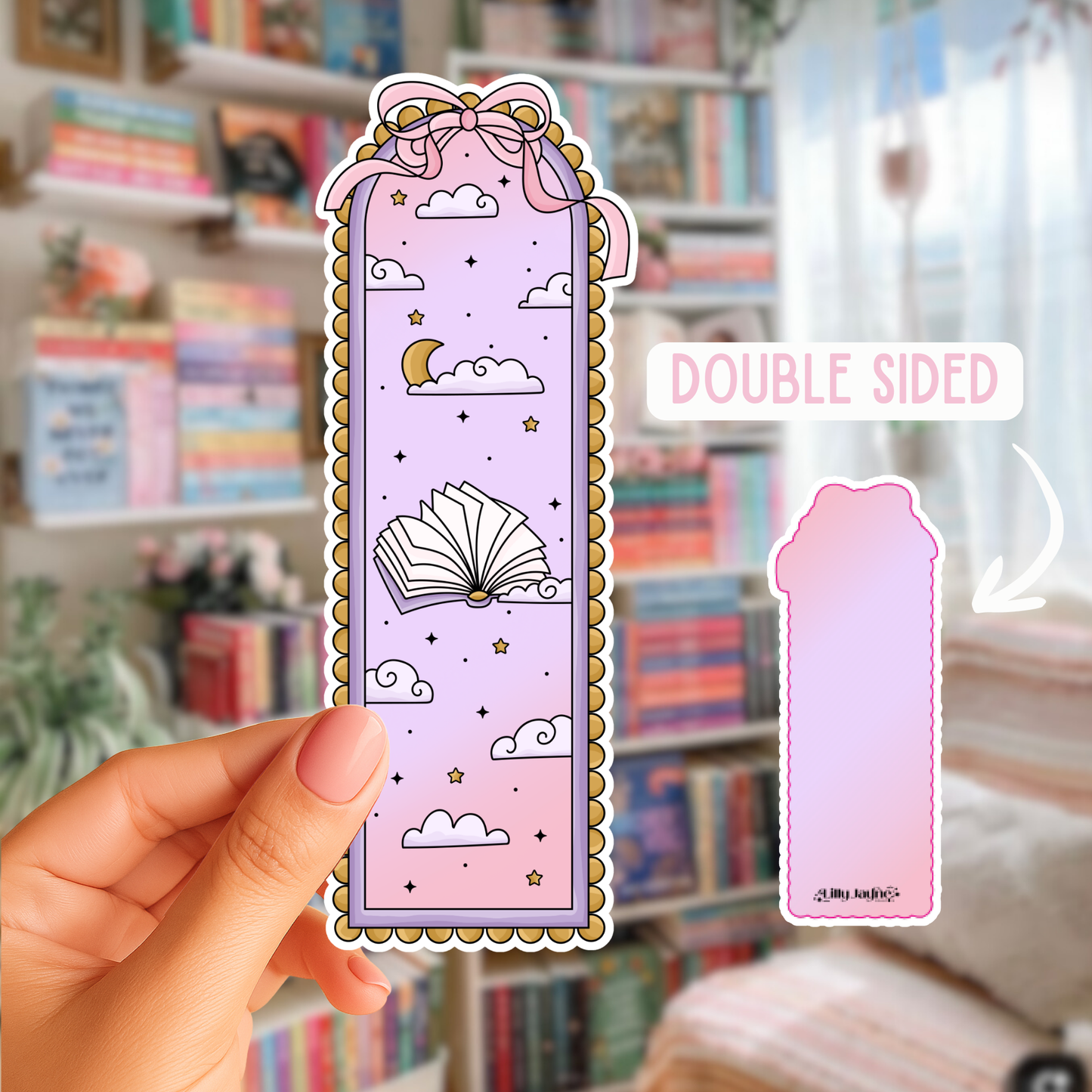 Decorative bookmark with cloud and book design held by a hand in front of a bookshelf.