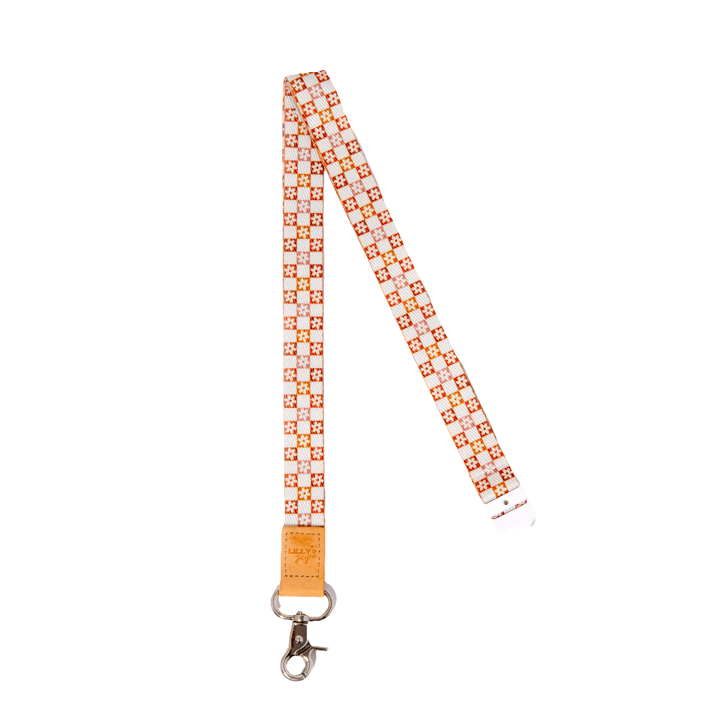 A white lanyard with orange floral patterns, featuring a faux leather trim and a metal clasp.