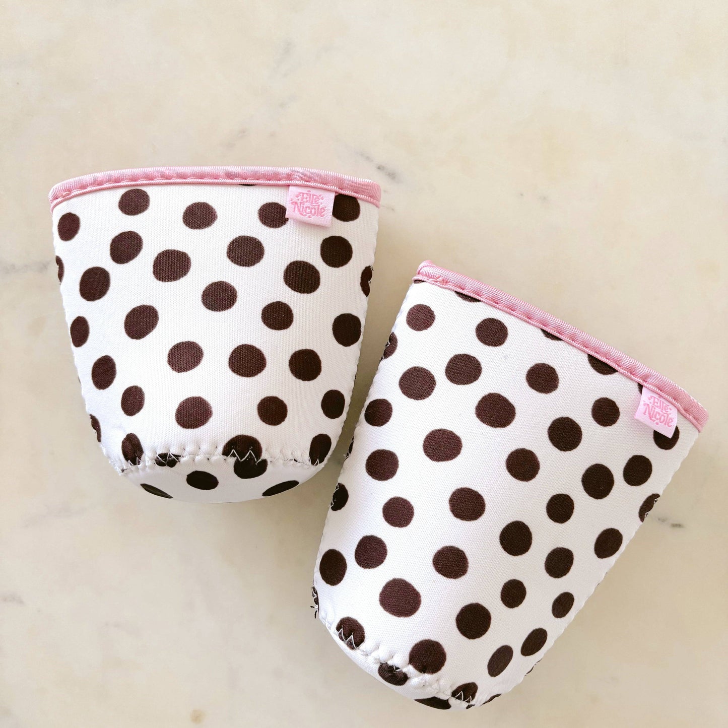 Pair of polka dot baby booties with pink trim on a light background