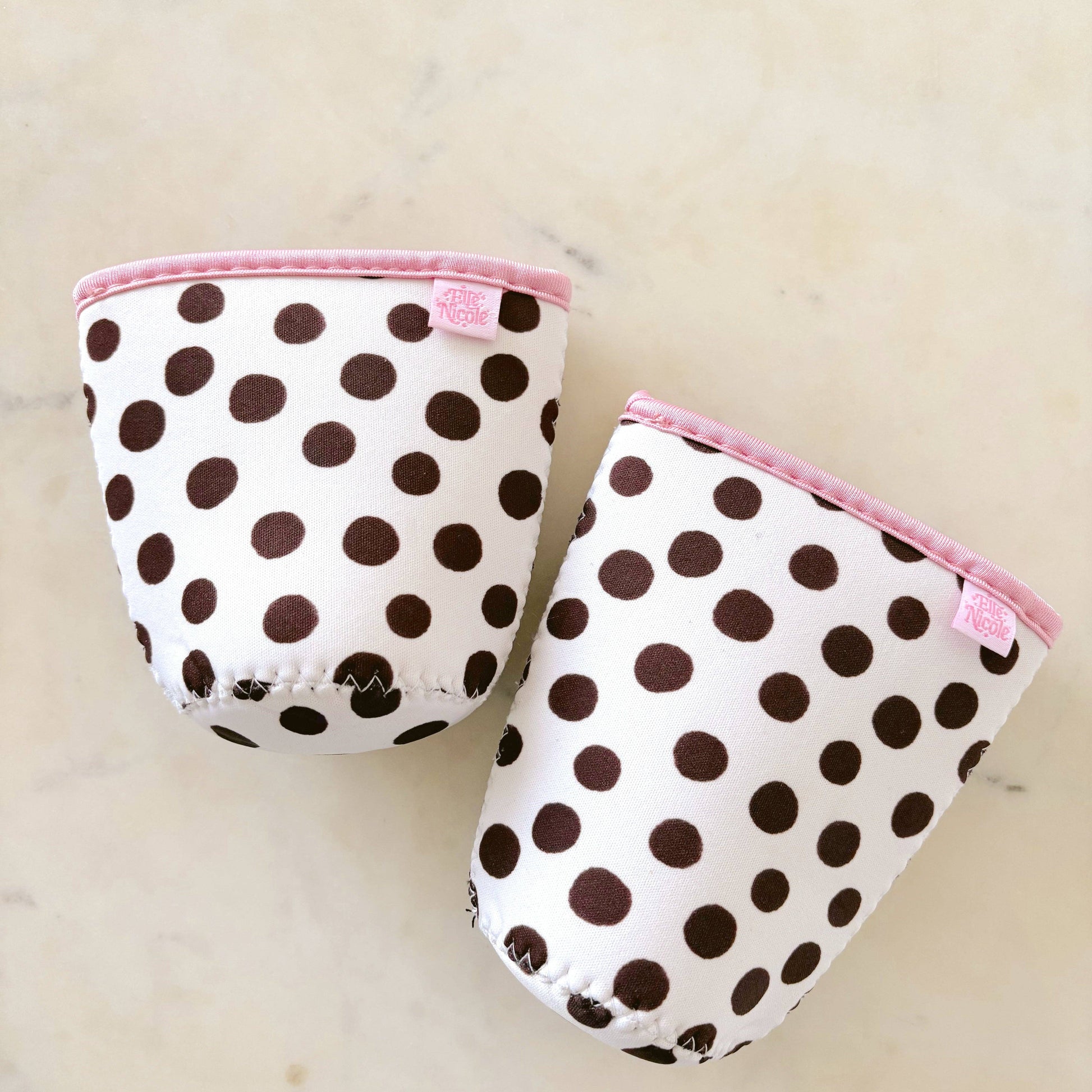 Pair of polka dot baby booties with pink trim on a light background