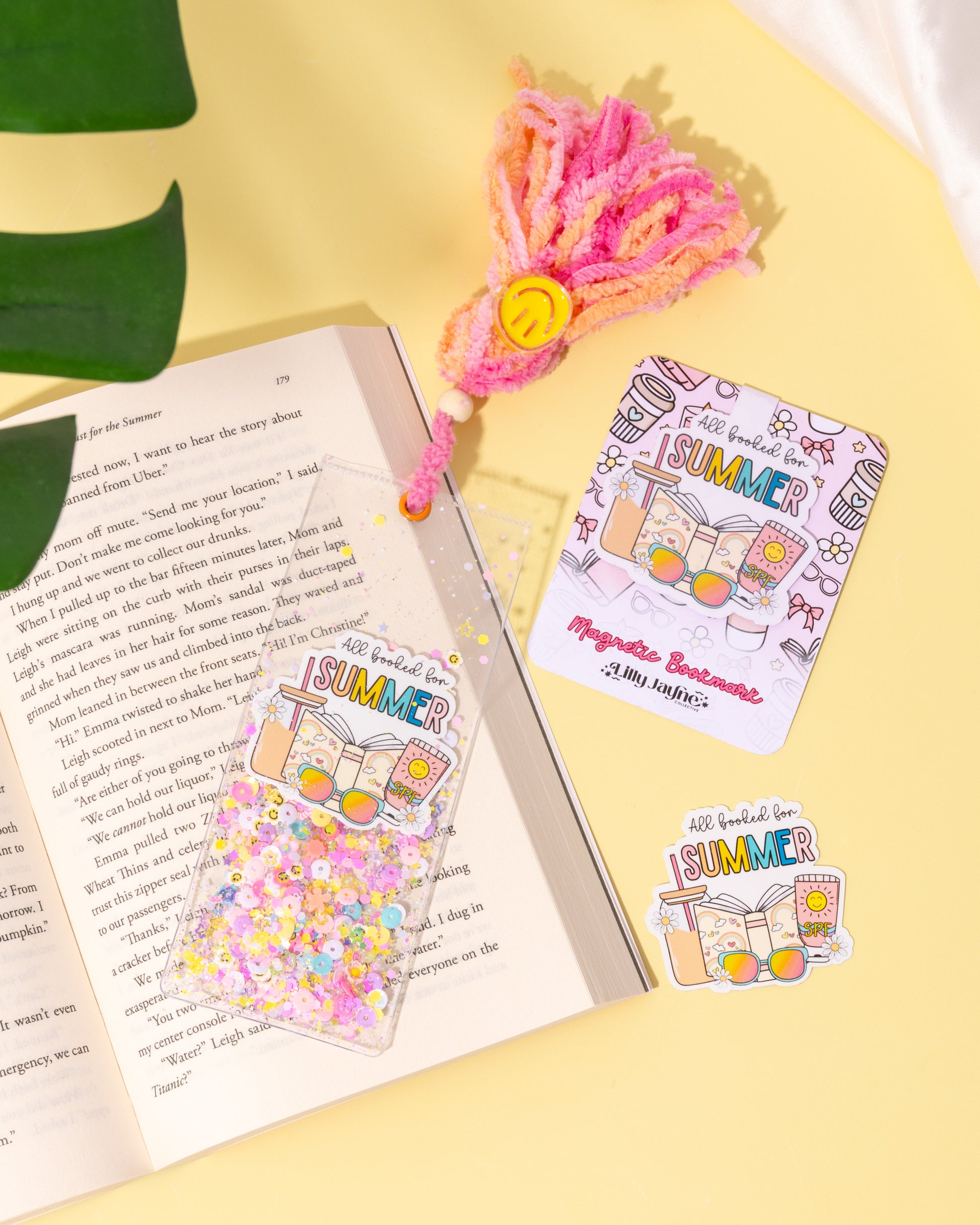 Colorful bookmarks and stickers on an open book with a decorative item on a yellow surface.
