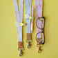 Glasses case with floral strap, pen holder, and glasses on a yellow background