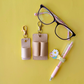 Glasses, keychain pouches, pen, and flower on a yellow background