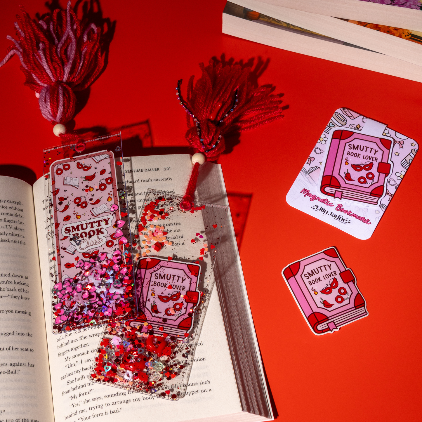 Decorative bookmarks and stickers with 'Smutty Book Lover' design on a red background.