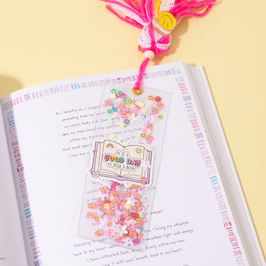 Open book with a decorative page featuring a small book and pink confetti on a yellow background.
