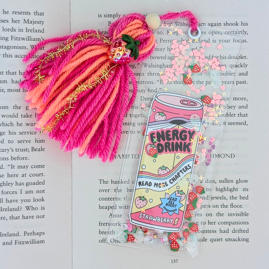 Colorful yarn hair extension with a 'Energy Drink' themed bookmark on an open book.