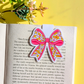 Checkered bow bookmark on an open book with a yellow background