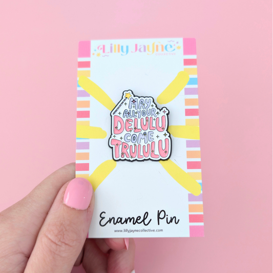 Enamel pin packaging with colorful design and text on a pink background