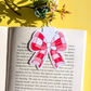 Pink and white bow-shaped bookmark on an open book with a yellow background