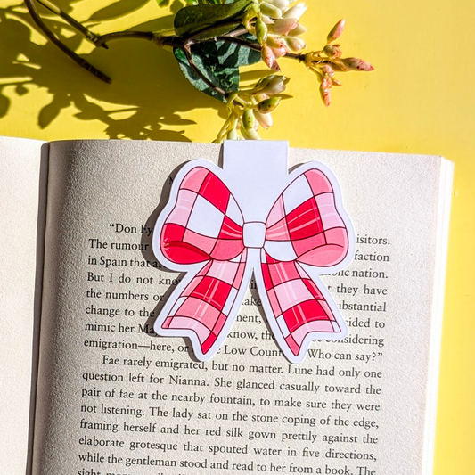 Pink and white bow-shaped bookmark on an open book with a yellow background