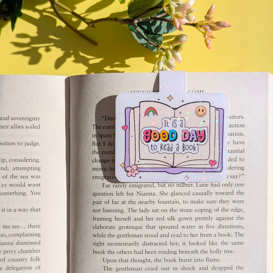 Book with a bookmark that says 'It is a good day to read a book' on a yellow background