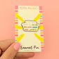 Enamel pin packaging with colorful design and text on a pink background