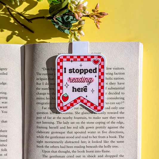 Book with a red and white checkered bookmark saying 'I stopped reading here' on a yellow background.
