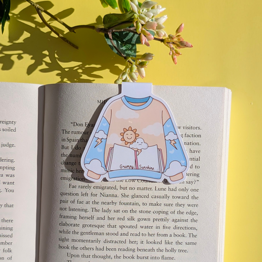 Open book with a sticker of a person wearing a sweatshirt with a sun design on a yellow background