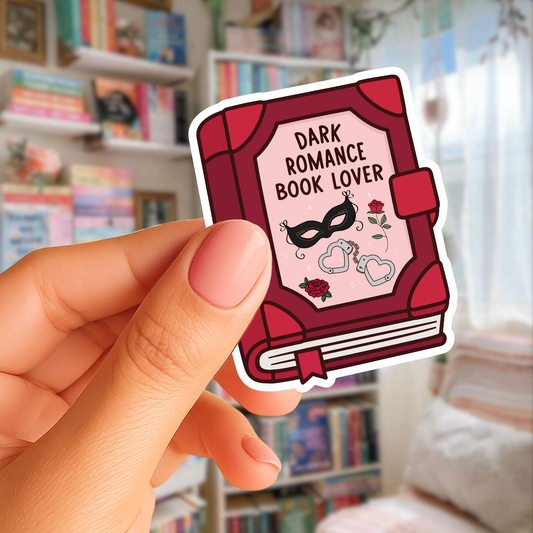 Sticker of a red book titled 'Dark Romance Book Lover' held by a hand in front of a bookshelf.