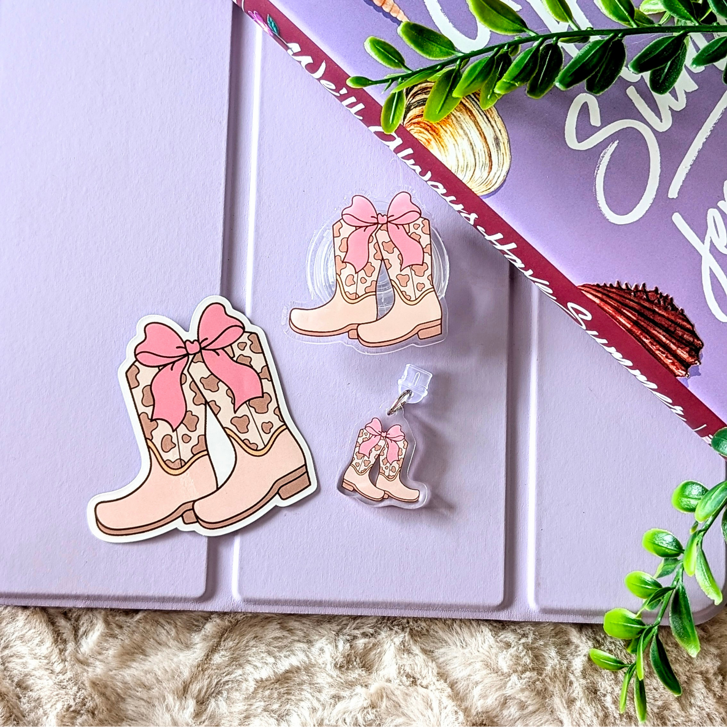 Cowboy boot-shaped stickers with pink bows on a purple surface with green leaves.
