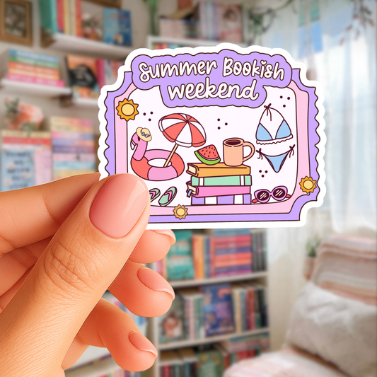 Sticker with 'Summer Bookish Weekend' design held by a hand in front of a bookshelf.