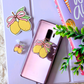 Phone case with lemon and bow design on a light purple surface with decorative items.