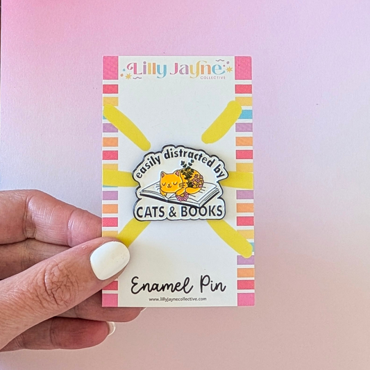 Enamel pin packaging with a colorful design and text on a pink background