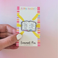 Enamel pin on a card held by a hand with a colorful background