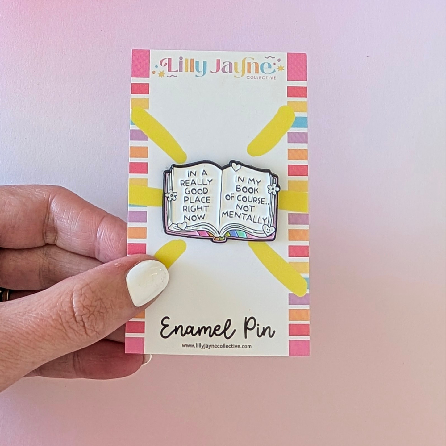 Enamel pin on a card held by a hand with a colorful background