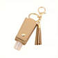 Hand sanitizer keychain with beige pouch and gold tassel on a white background