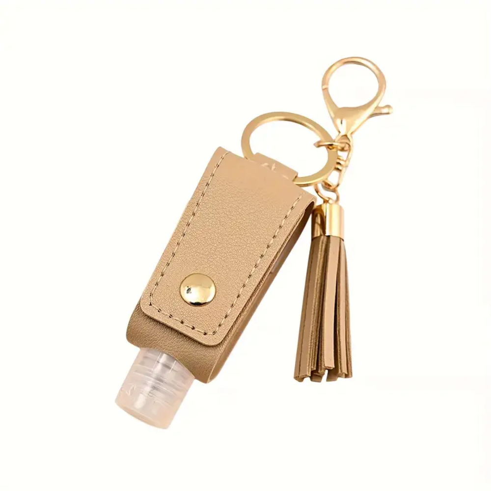 Hand sanitizer keychain with beige pouch and gold tassel on a white background