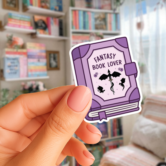 Sticker with 'Fantasy Book Lover' design held by a hand in front of a bookshelf.