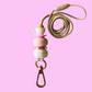 Necklace with pink and white beads and a teapot charm on a light gray background