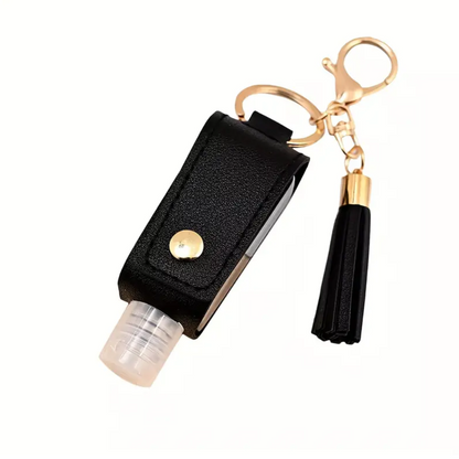 Black keychain with a small bottle and tassel on a white background