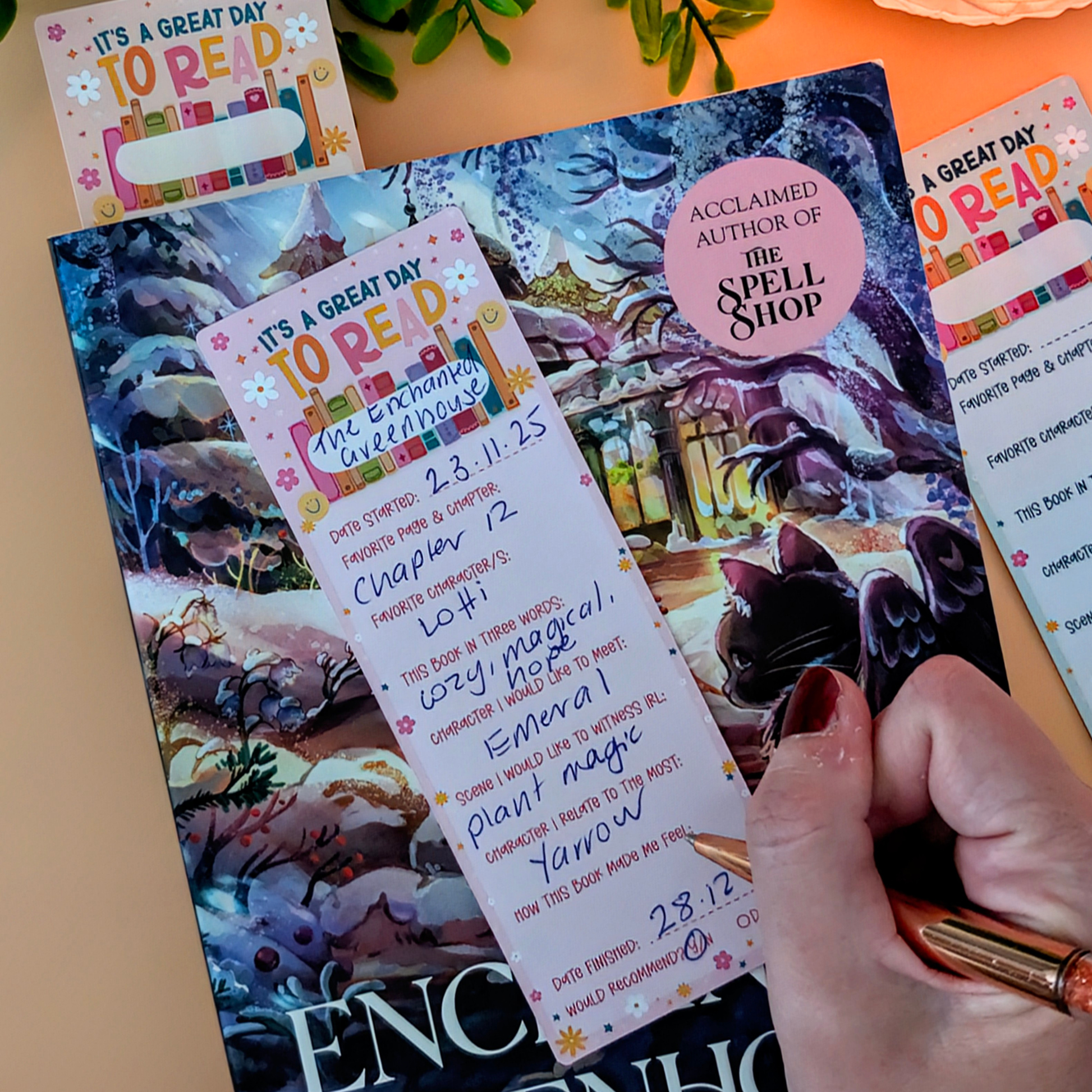 Book with bookmarks and a hand holding a pen on a table