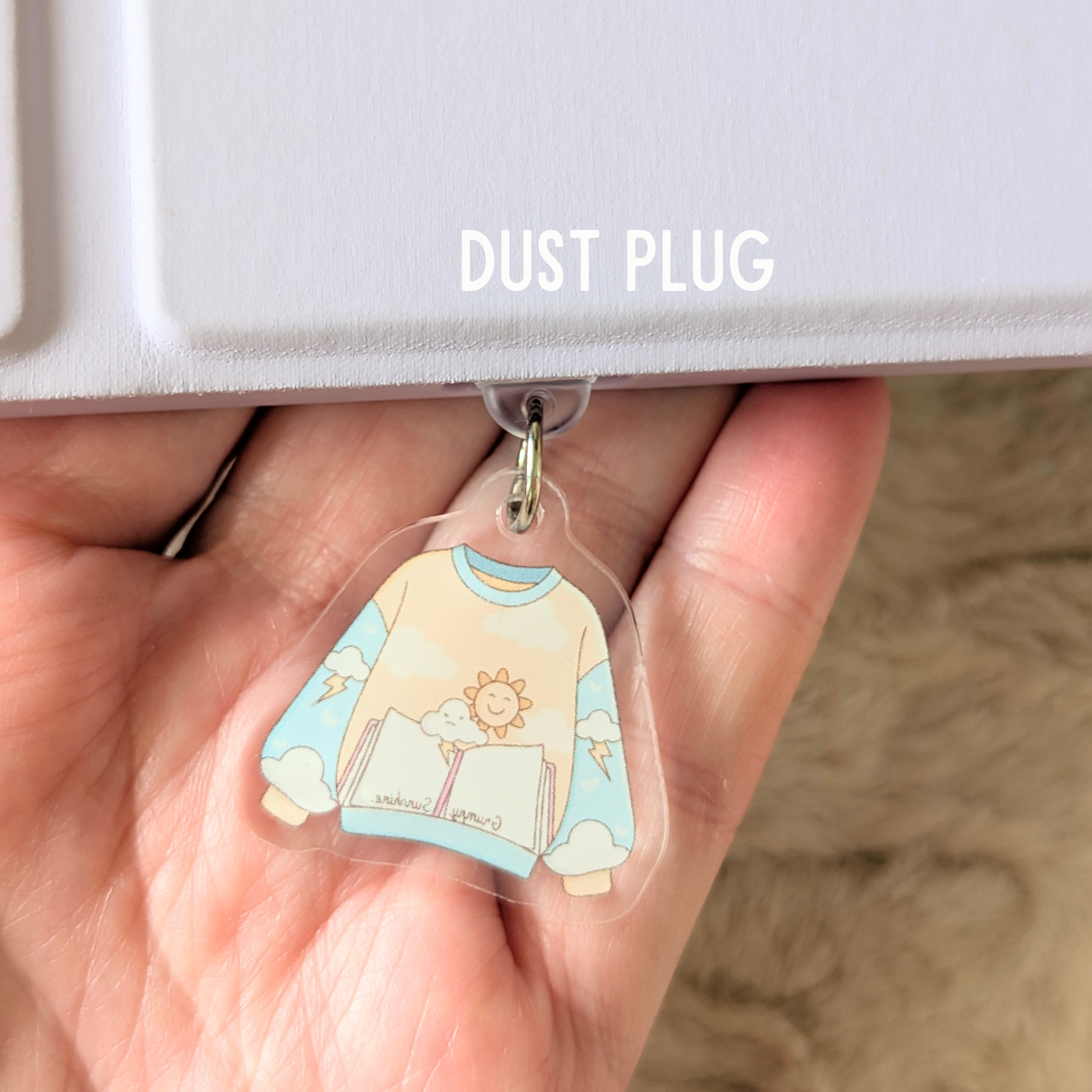 Clear dust plug with cartoon sweater design held in a hand