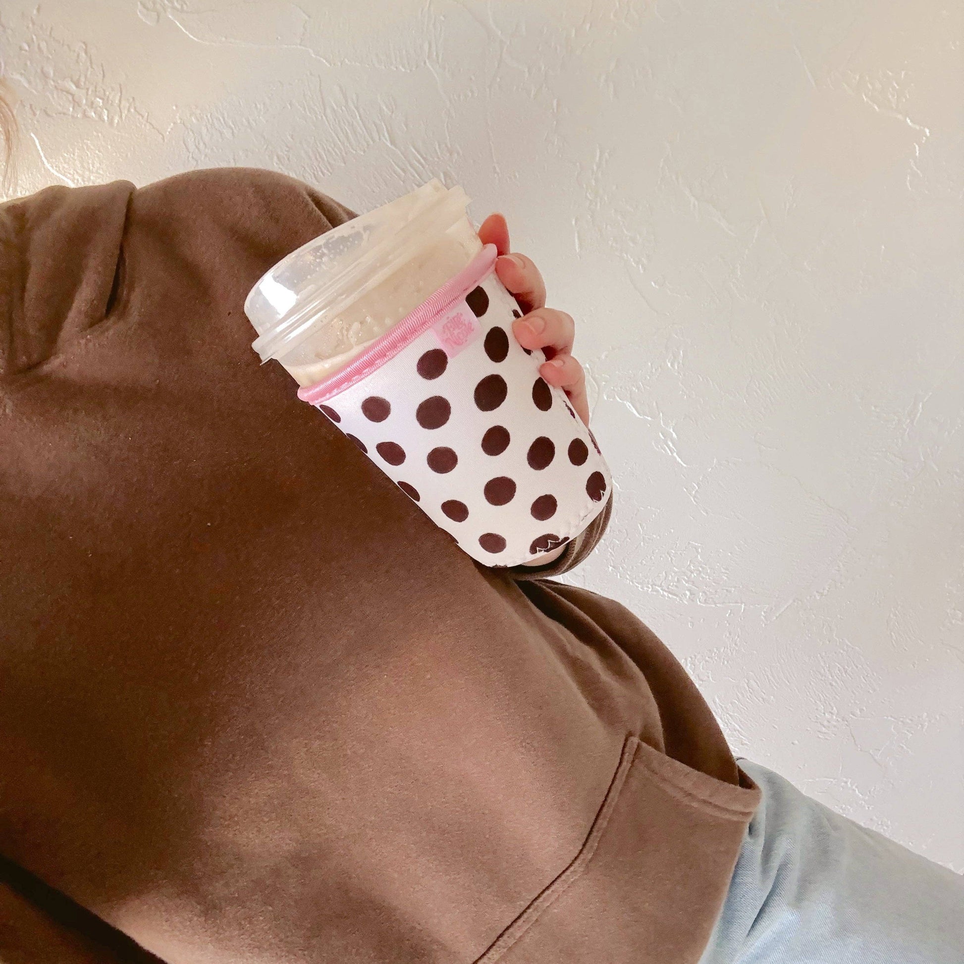 Person holding a polka dot cup against a plain background