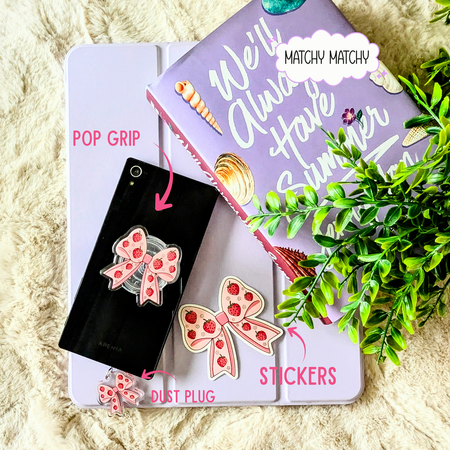 Phone accessories including a pop grip, dust plug, and stickers on a textured surface with greenery.