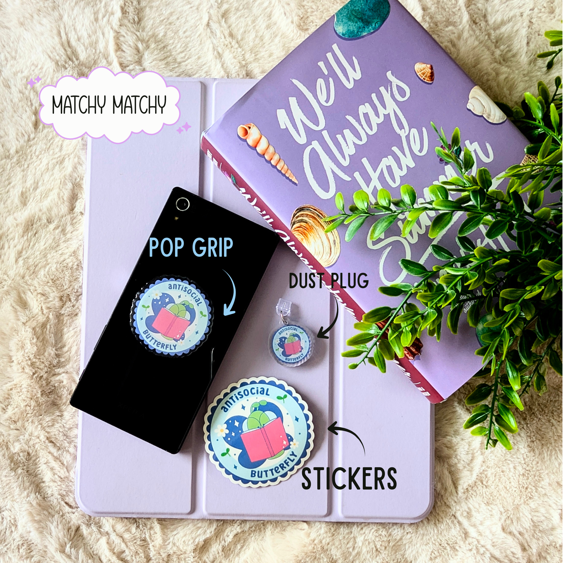 Phone case with pop grip, dust plug, and stickers on a book with decorative text.