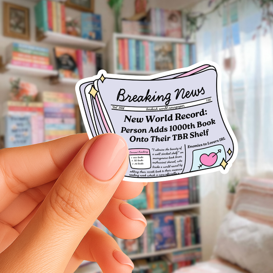 Hand holding a sticker with 'Breaking News' text in front of a bookshelf.