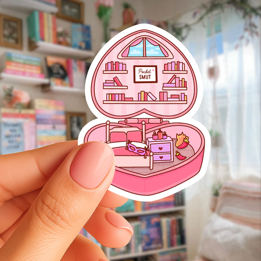 Sticker of a pink bedroom scene held by a hand in front of a bookshelf.