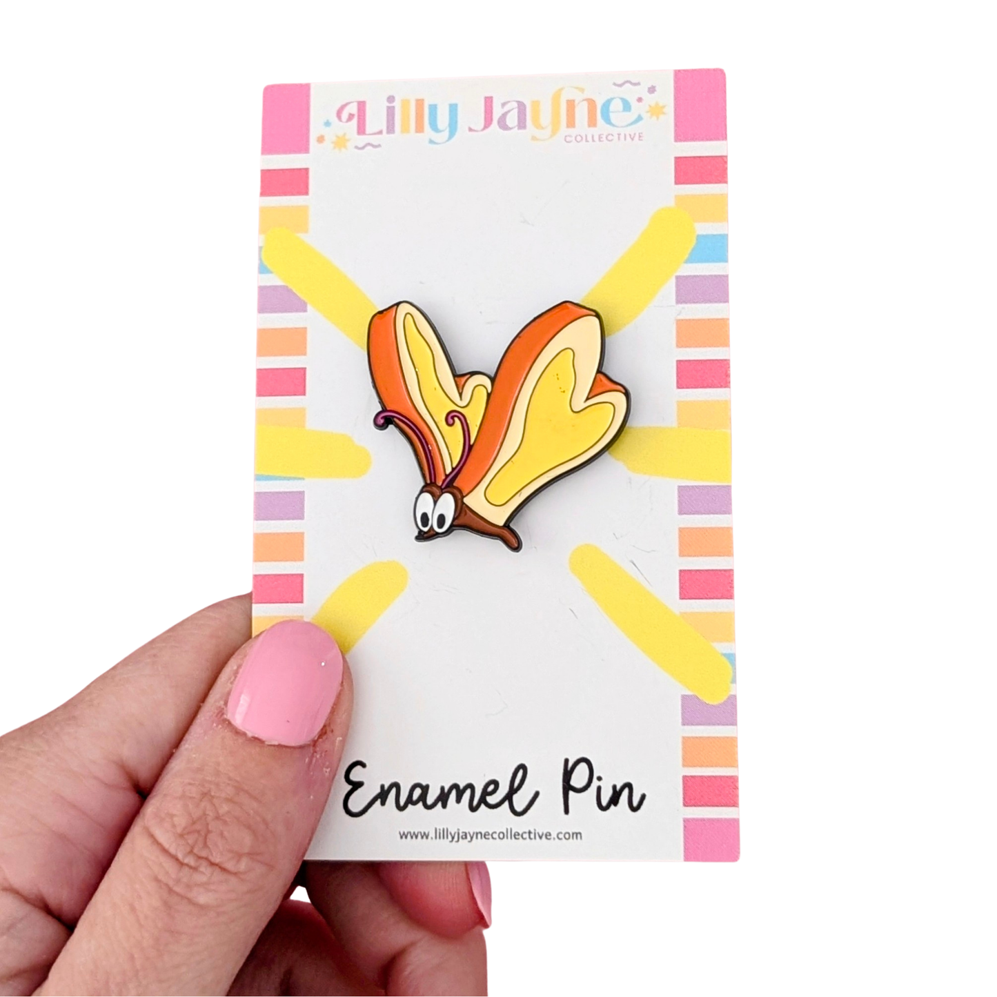 Lilly Jayne enamel pin on a colorful card held by a hand with pink nail polish.