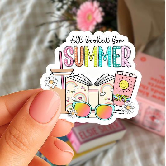 Sticker with 'All booked for Summer' text held by a hand, with a blurred background.