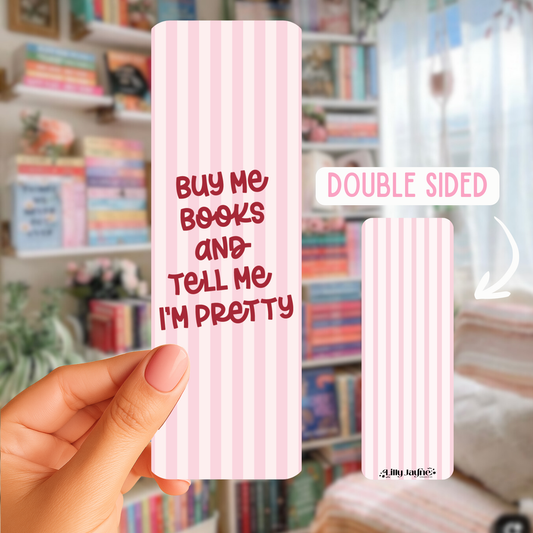 A hand holding a buy me book and tell me im pretty double sided bookmark